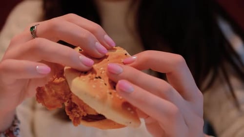 Woman Eating Burger Close Up in Indoor Setting