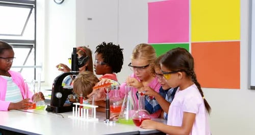 Children Conduct Science Experiment in Classroom with Goggles