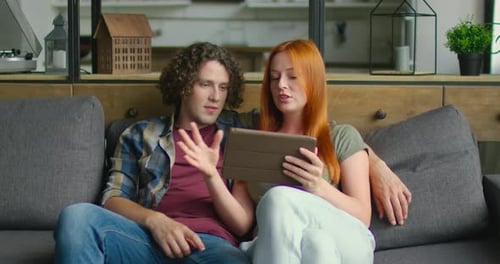 Couple Relaxing on Couch Together Using Tablet