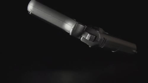 A Gun Falls On A Black Desk