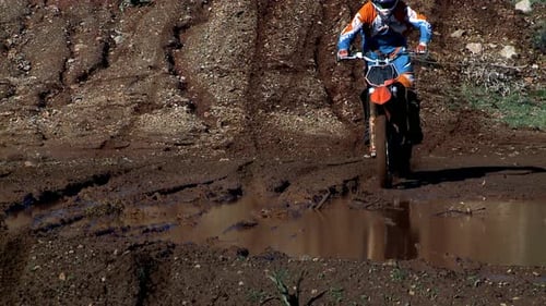 Motorcycle Splashing Through Muddy Puddle on Rural Track