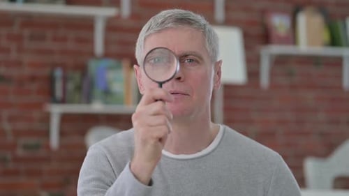 Man Looking Through Magnifying Glass Indoors