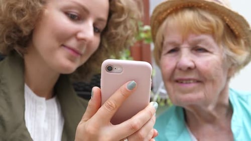 Young Woman Showing a Phone to Senior Woman