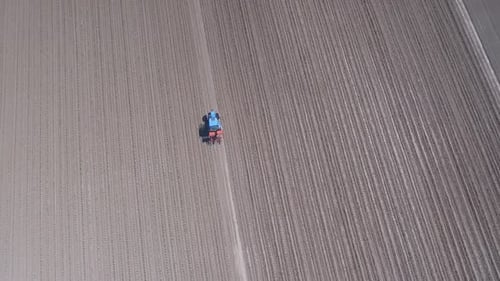 Tractor in a field ploughing, countryside aerial view