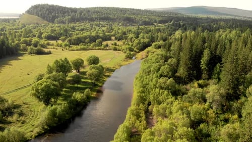 Luftflug einer Drohne über Gebirgsfluss, Feld, Wald und Pfad