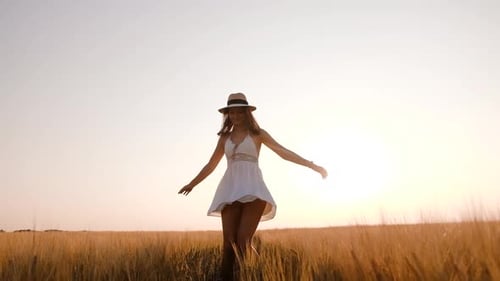 Happy Free Young Woman Dancing and Spinning Around in Slow Motion Across Field Touching Ears of