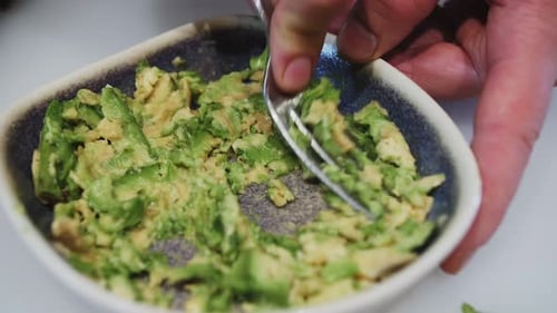 Mashing an Avocado with a Fork in Bowl