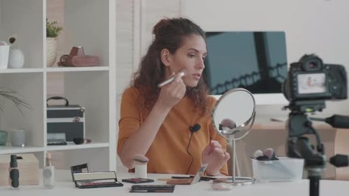 Woman Applies Makeup in Front of a Camera