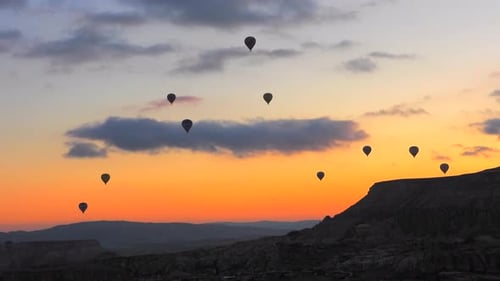 Hot Air Balloons Ascend in Landscape at Sunset