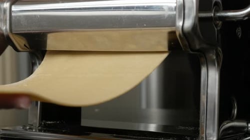 Pasta Dough being Rolled Through Pasta Machine