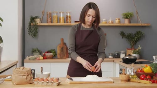 Woman Cracking Egg into Flour for Baking at Home