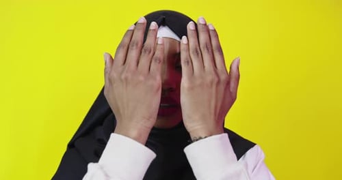 Woman Raising Hands to Face in Studio