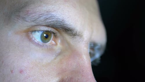 Eyes and Face of a Young Man Working at a Computer on a Black Background