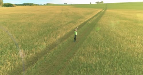 Sporty Child Standing in Green Wheat Field with Raised Hands Up