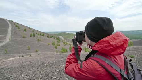 Photographer with Vintage Camera on Hillside Taking Pictures