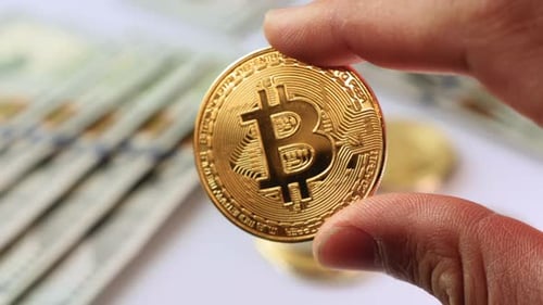 Hand Holding Gold Bitcoin with Currency Background