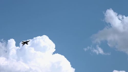 Fighter Jet Flying Through a Cloudy Blue Sky