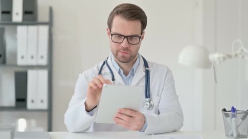 Male Doctor Using Tablet in Bright Office