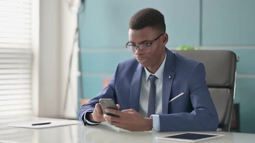 Successful Young African Businessman Celebrating on Smartphone