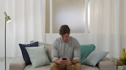 Man Relaxing on Sofa Using Smartphone