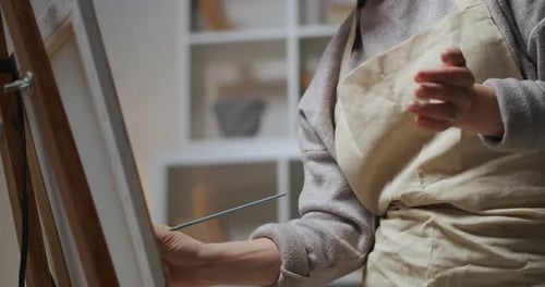 Young Adult Woman Painting on Canvas Indoors