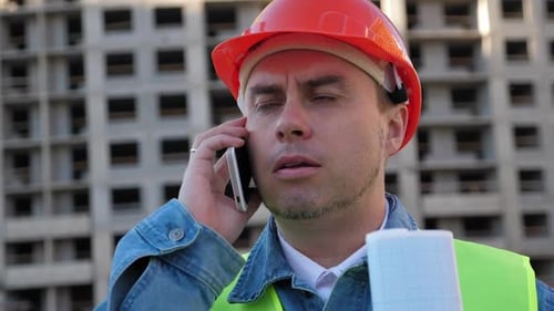 Worker Staff in Protective Helmet Using Smartphone at Construction Site