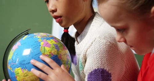 Crianças em idade escolar olhando para o globo na sala de aula da escola