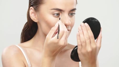 Woman Applying Eyebrow Makeup in Studio Setting