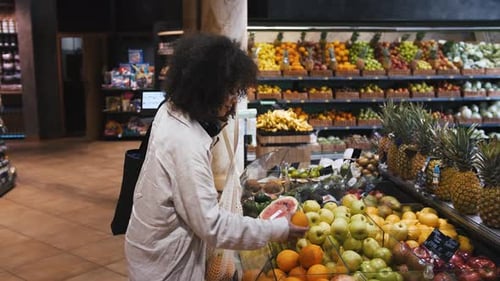 Mujer afroamericana con bolsas ecológicas y auriculares en el cuello