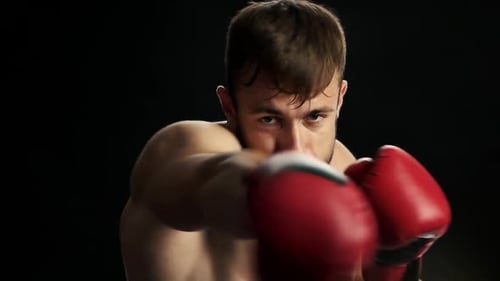 Man Boxing with Red Gloves in Dark Studio