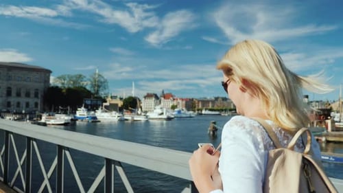 Woman Talking on the Phone on the Go. Walking Over the Bridge in the Background of the Stockholm