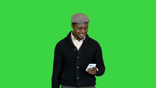 Junger afrikanischer Mann benutzt Handy auf einem Greenscreen-Chroma-Key