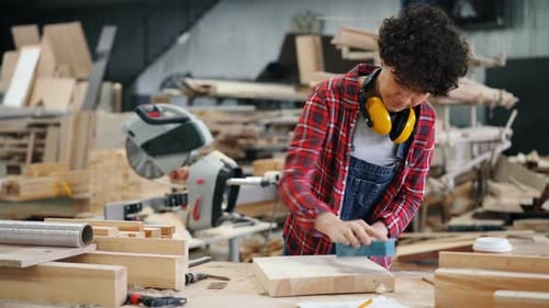 Young Woman Polishing Piece of Wood Working in Timber Workshop Alone