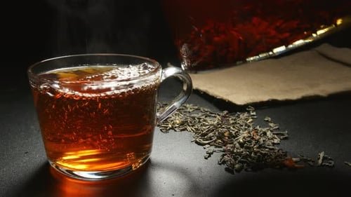 Relleno de té caliente en una taza de una tetera