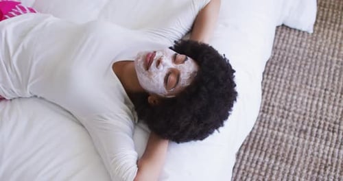 Woman Relaxes With Facial Mask Lying On Bed