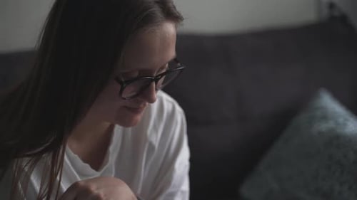 Woman in Glasses Thinking Indoors on a Couch