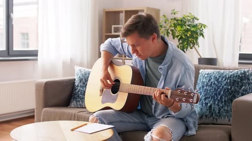 Young Man Plays Guitar and Writes Song