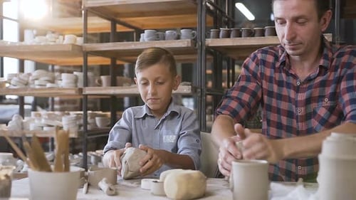 Boy and Man Making Pottery Together in Studio