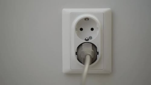 Weibliche Hand steckt einen Netzstecker in die Wandsteckdose
