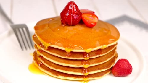 Pancakes Stacked High with Strawberries and Syrup
