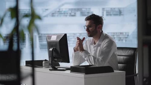 A Serious Man Sits at a Computer in the Office and Thinks