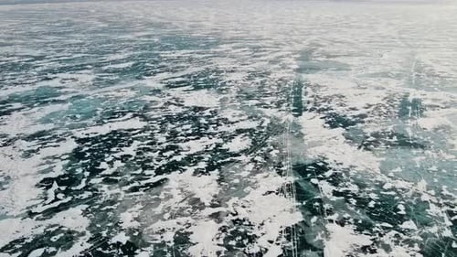 A picturesque pattern of lake ice formed by cracks, islands of snow and bubbles