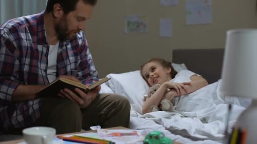 Father Reads Bedtime Story to Young Daughter