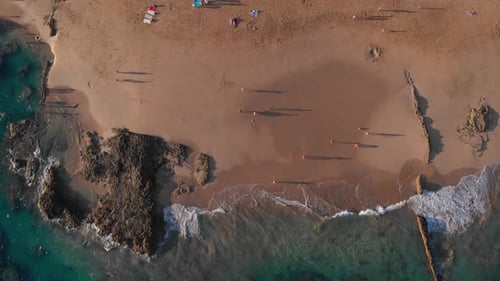 Picturesque summer flight directly above people walking by clear turquoise ocean sea water and waves