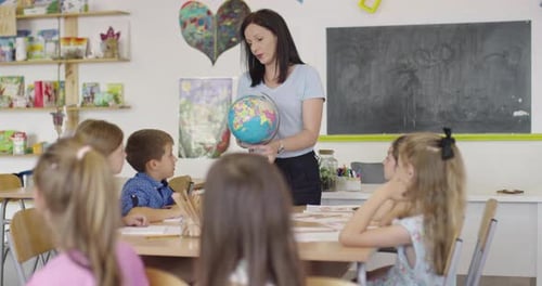 Female Teacher with Kids in Geography Class Looking at Globe