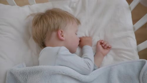Small Attractive Baby Sleeps Soundly During Day on a Soft Comfortable Pillow Covered with a Blanket