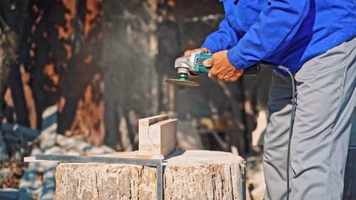 Steinbearbeitung aus Gestein. Arbeiter in Handschuhen mit einem kleinen Winkelschleifer schneidet eine Granitplatte