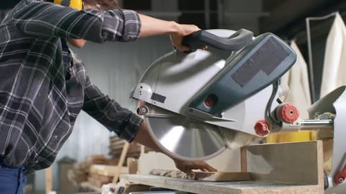 Carpenter cuts wood in workshop using chop saw