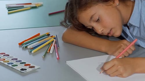 Girl Draws with Colored Pencil at Table