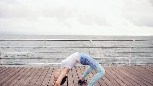 Joven atlética agachándose y estirándose en la playa junto al océano